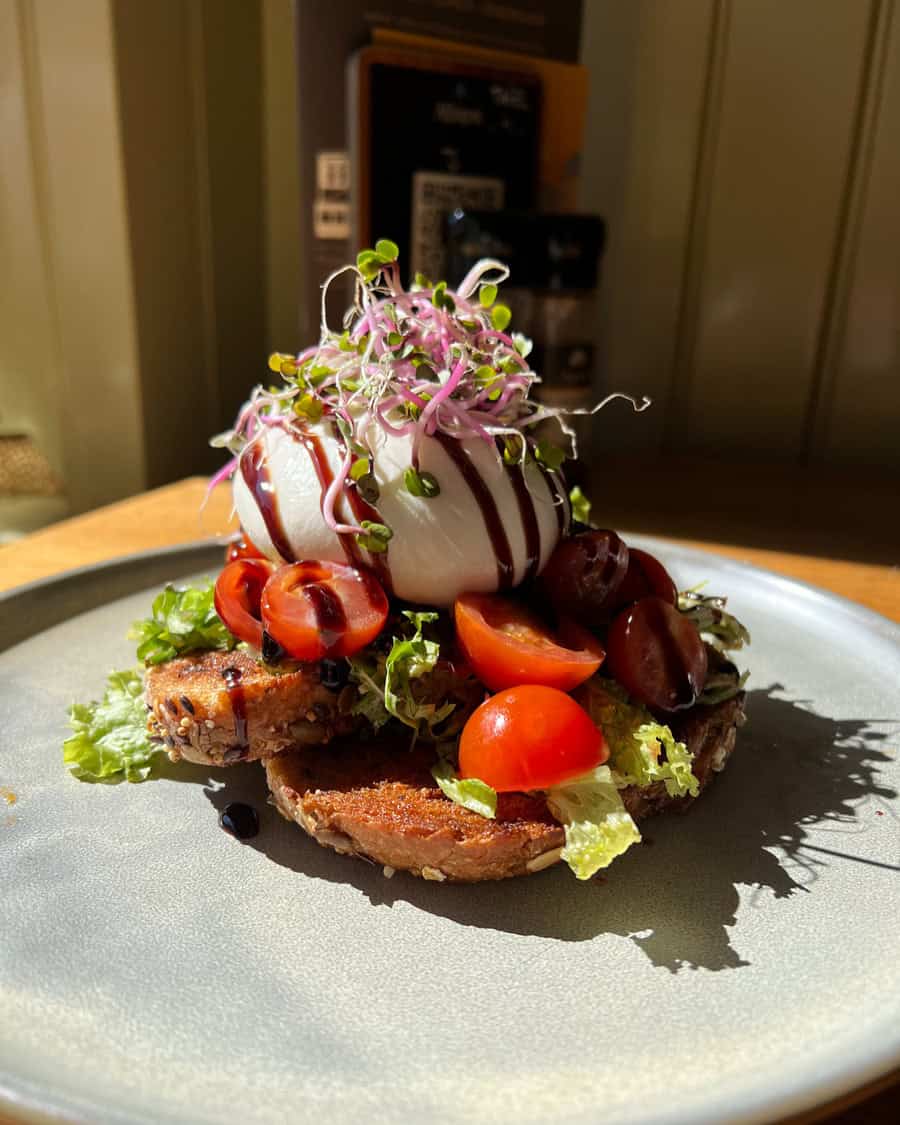Etagere met salade, geitenkaas, cherrytomaatjes en een bol ijs met saus en microgroenten.