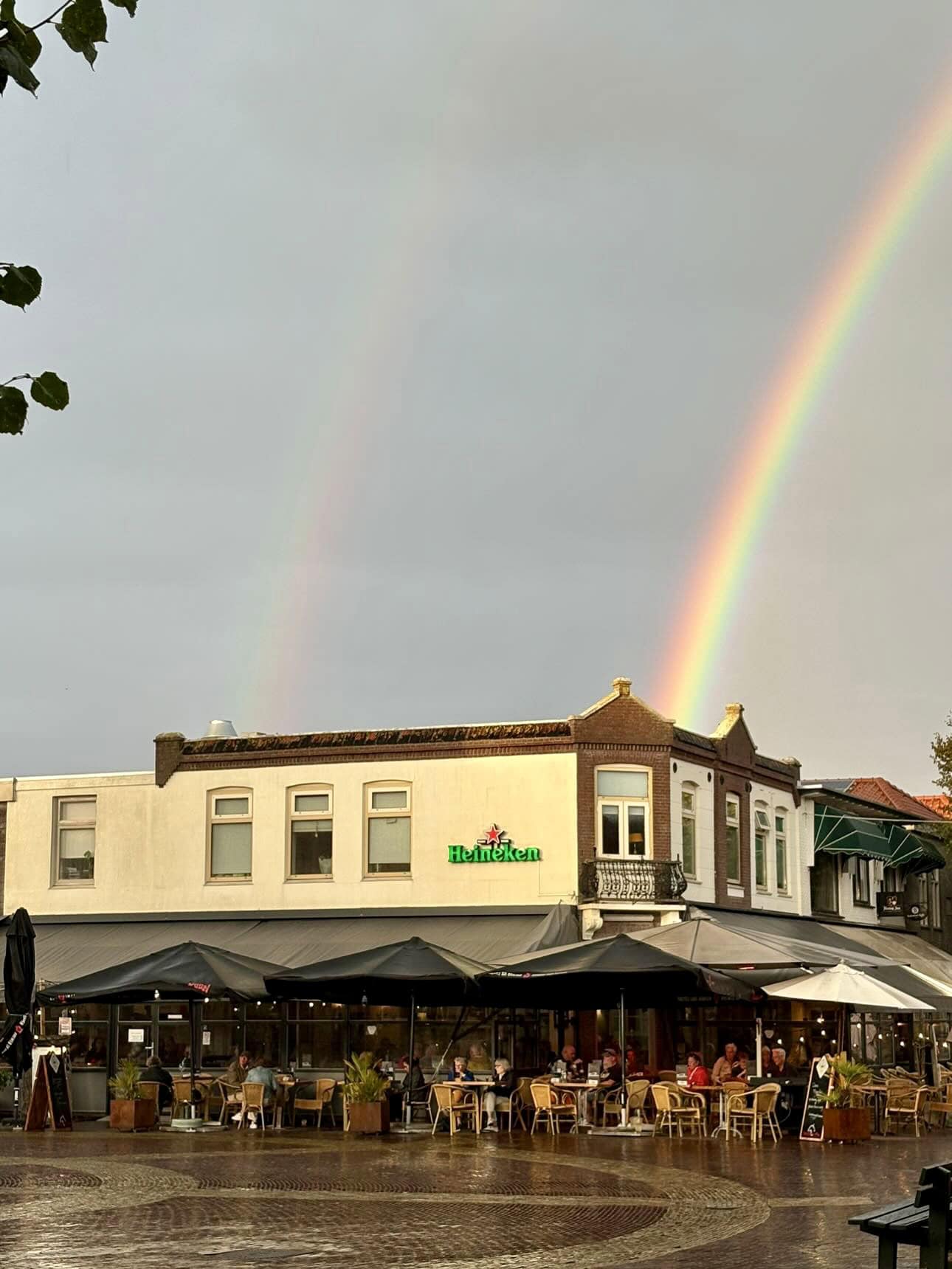 Kleurrijke regenbogen boven restaurant Flaman met terras op Terschelling.